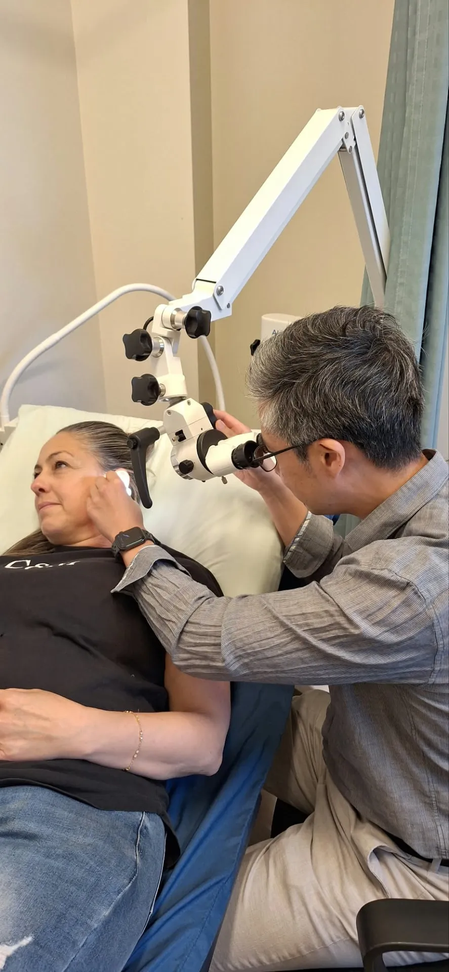 A doctor performing ear microsuction on a patient using a microscope