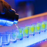 Shot glasses being poured on a bar