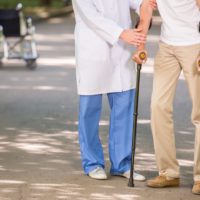 Close-up of doctor helping to his patient with osteoporosis to walk with crutches