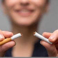 Close up portrait of young attractive woman breaking down cigarette to pieces