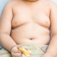 Big obese asian fay boy eating greasy unhealthy fried food