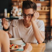 Unhappy man with eating problem staring at food in cafe