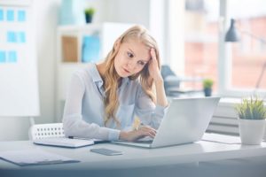 pale and tired woman working at a desk